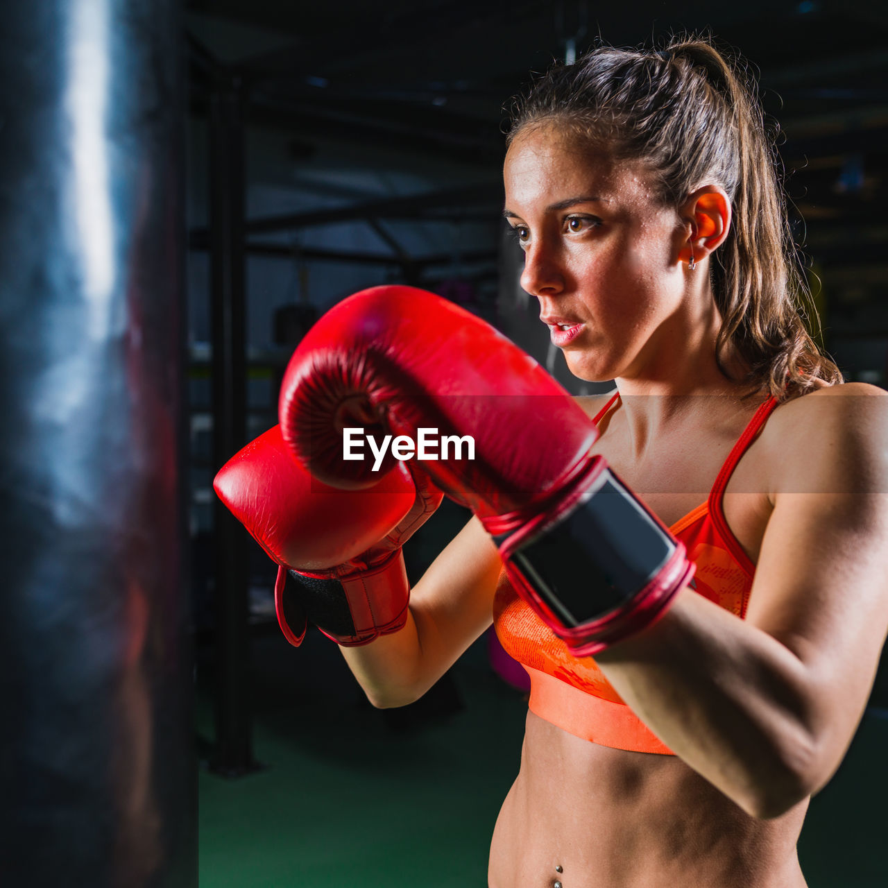 Female boxer punching bag in gym
