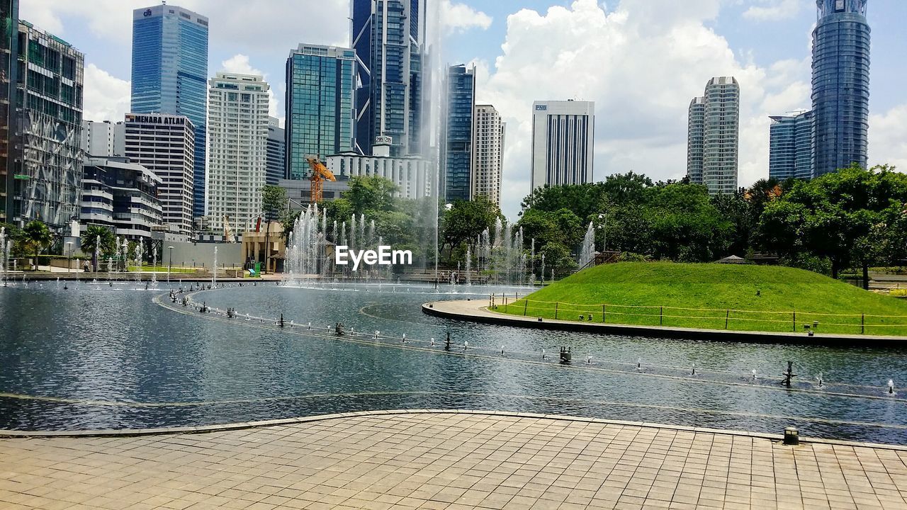 Fountain in city against sky