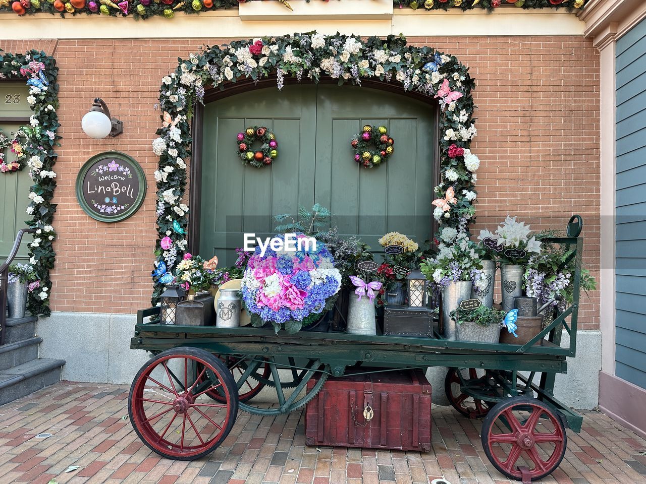 flowering plant, flower, architecture, plant, building exterior, decoration, built structure, no people, potted plant, building, nature, carriage, multi colored, day, outdoors, transportation, vehicle, bicycle, city, entrance, window, cart, wood, street, residential district, land vehicle