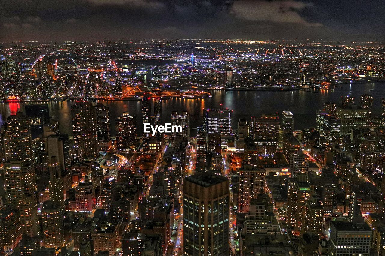 HIGH ANGLE VIEW OF ILLUMINATED CITY BUILDINGS AT NIGHT