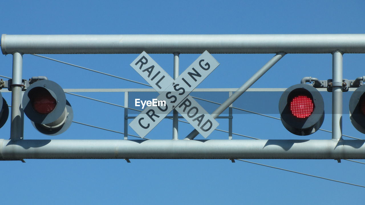 Low angle view of stoplight and road sign against blue sky