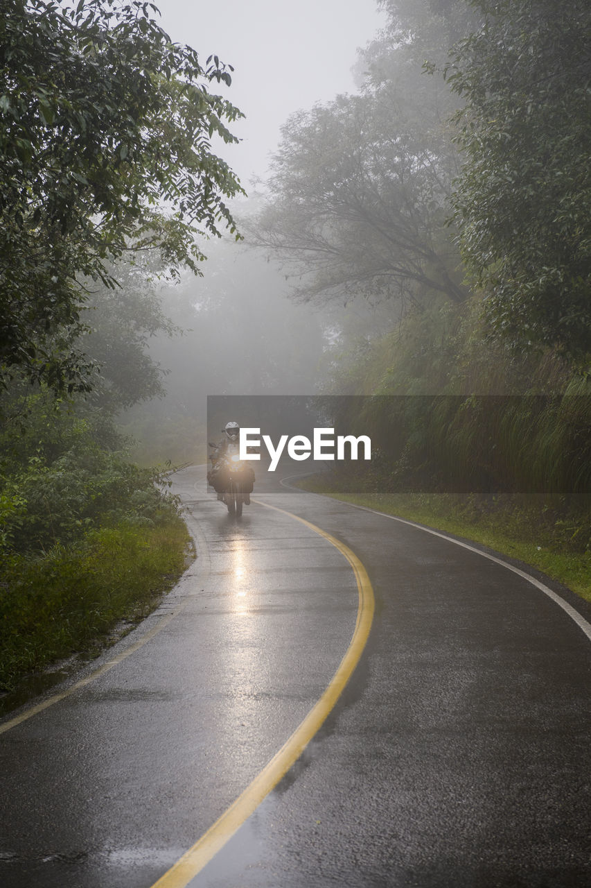 Woman riding touring motorbike through rain forest, jujuy / argentina