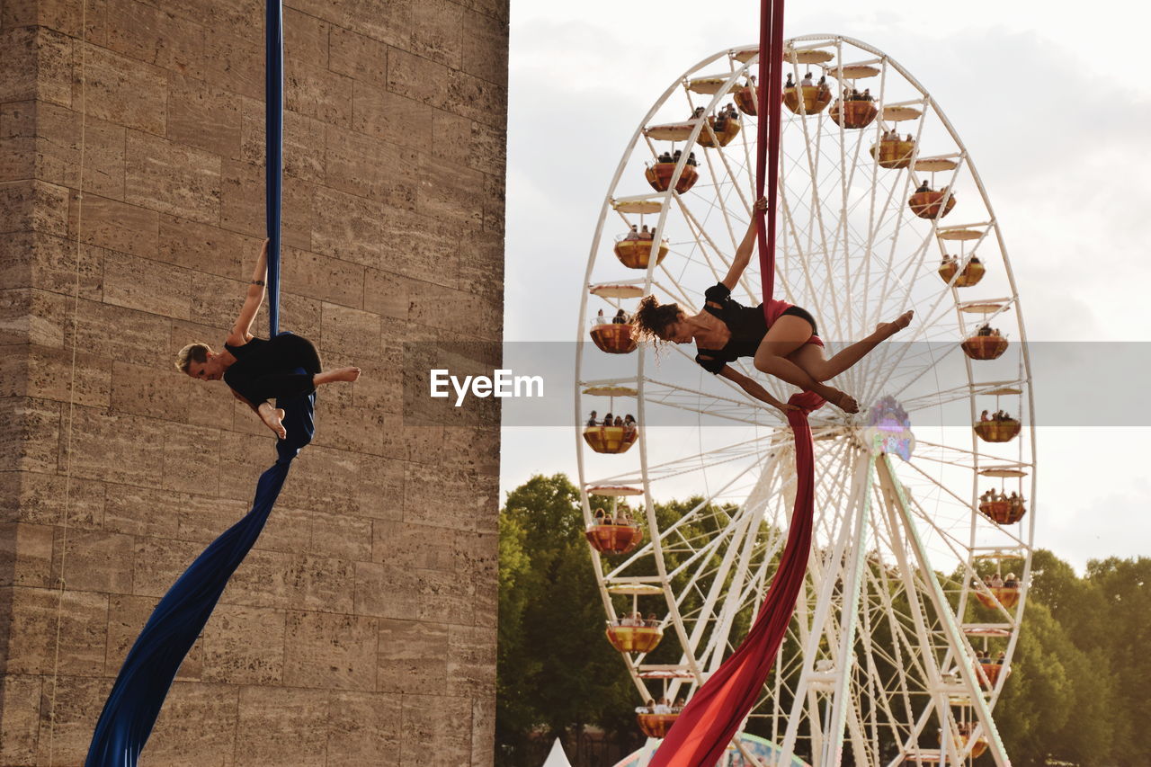 PEOPLE IN AMUSEMENT PARK RIDE AGAINST SKY