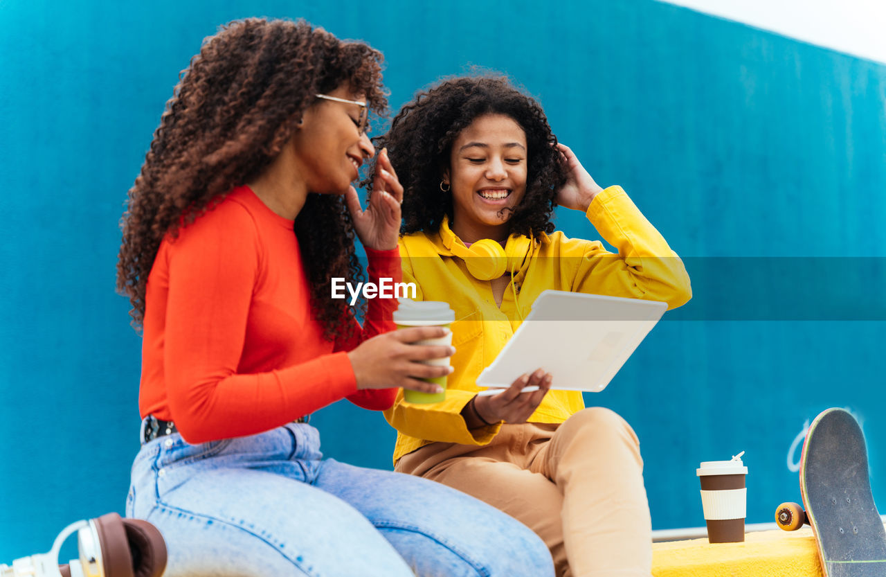 Smiling young females looking at digital tablet outdoors