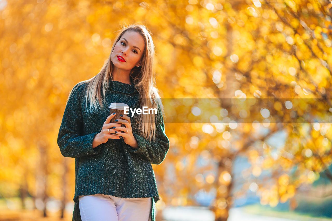 Young woman using smart phone during autumn