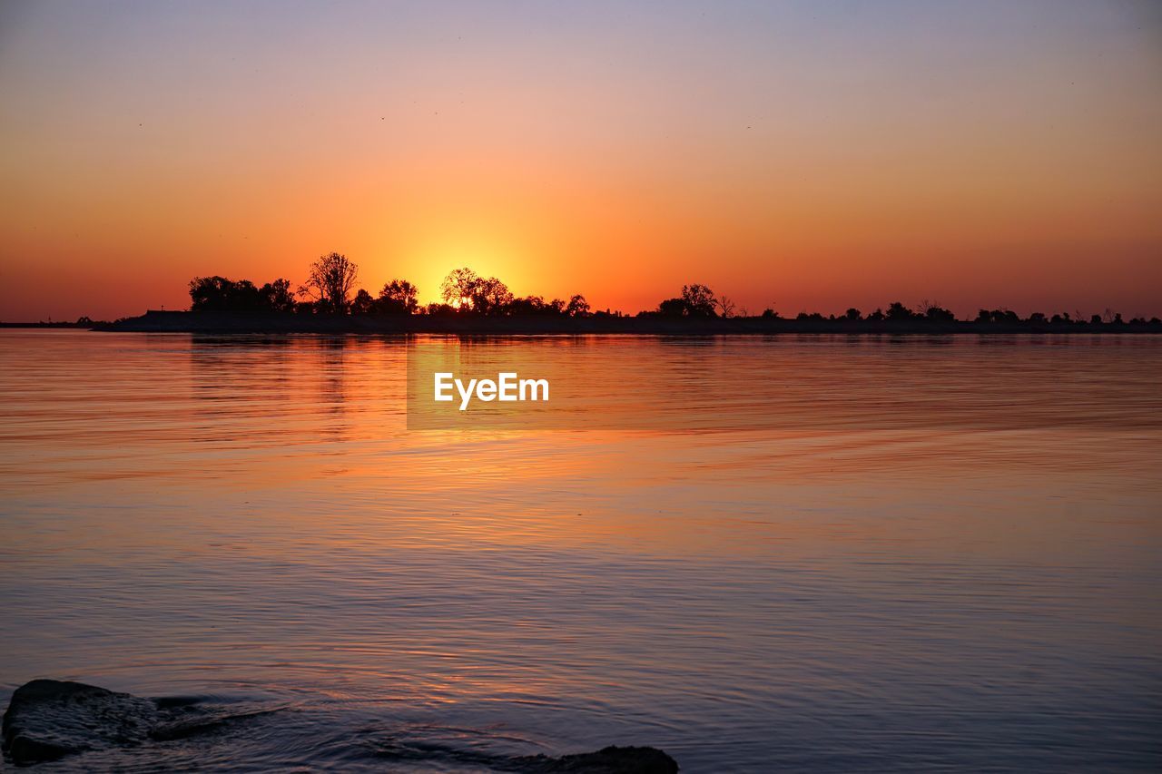 SCENIC VIEW OF LAKE AGAINST ORANGE SKY