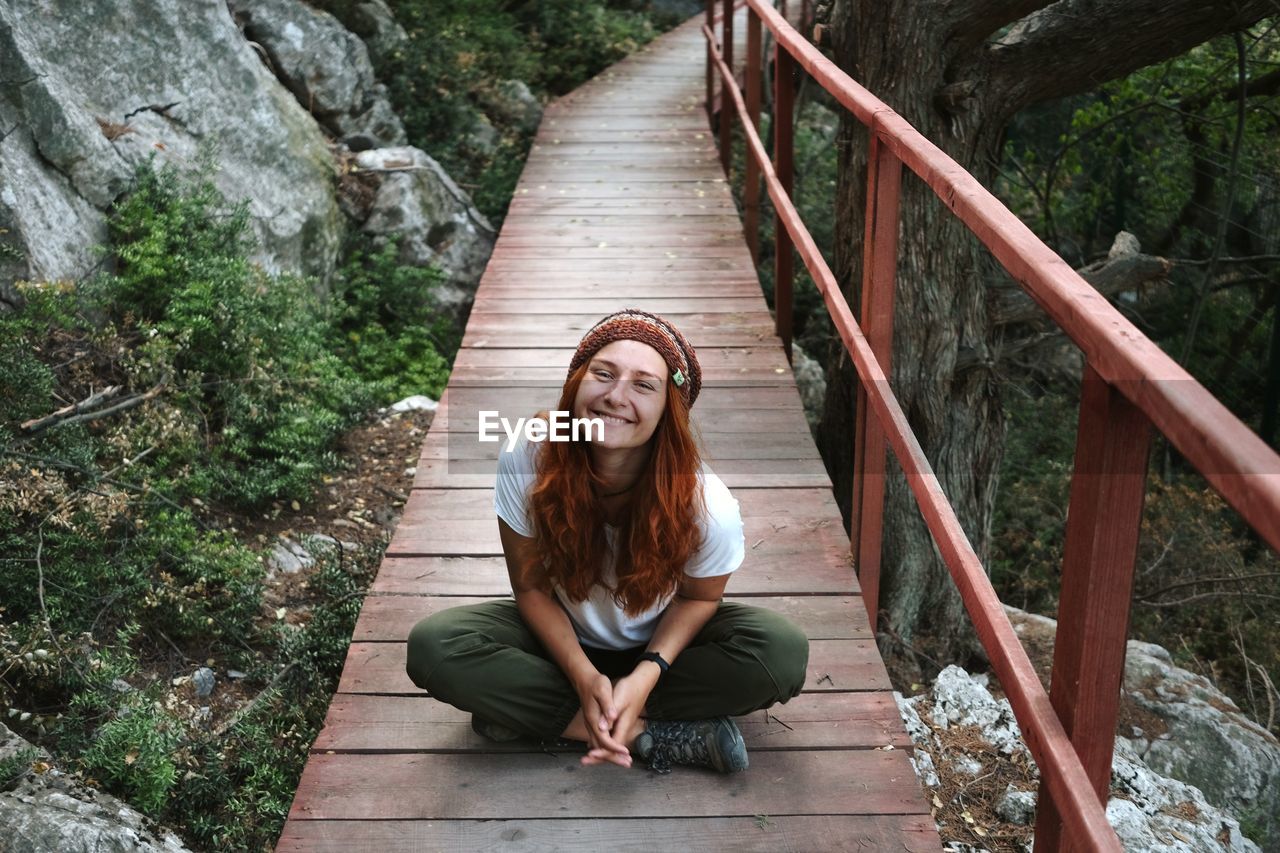 Portrait of young woman sitting on staircase in the forest