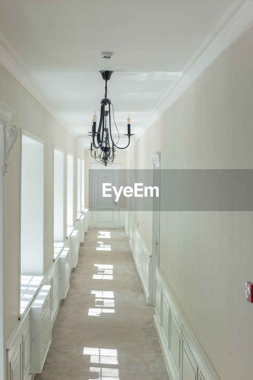 room, architecture, indoors, ceiling, corridor, hall, arcade, lighting equipment, floor, no people, interior design, building, home, white, built structure, diminishing perspective, absence, lighting, the way forward, vanishing point, railing