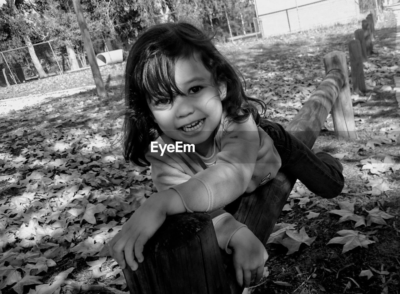 Portrait of smiling girl sitting on railing