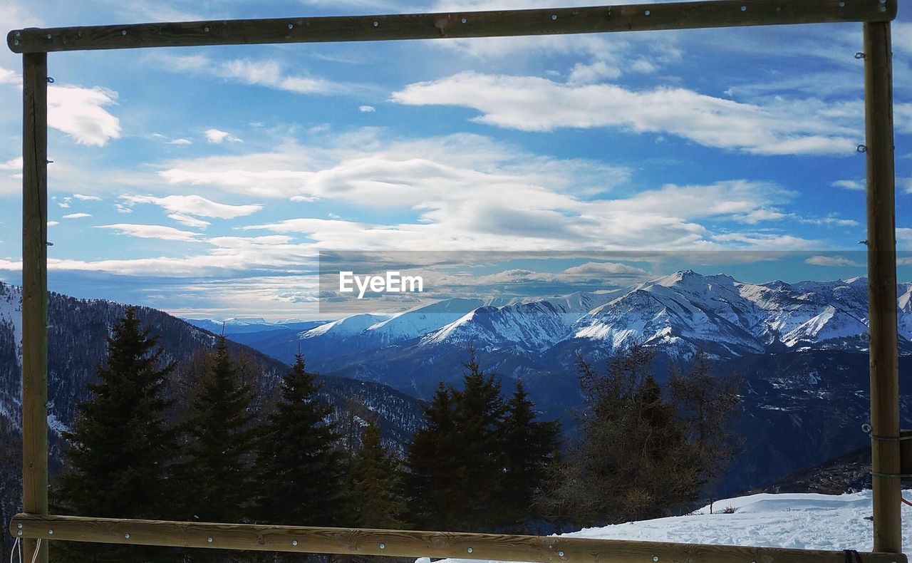 Scenic view of snowcapped mountains seen through wooden frame