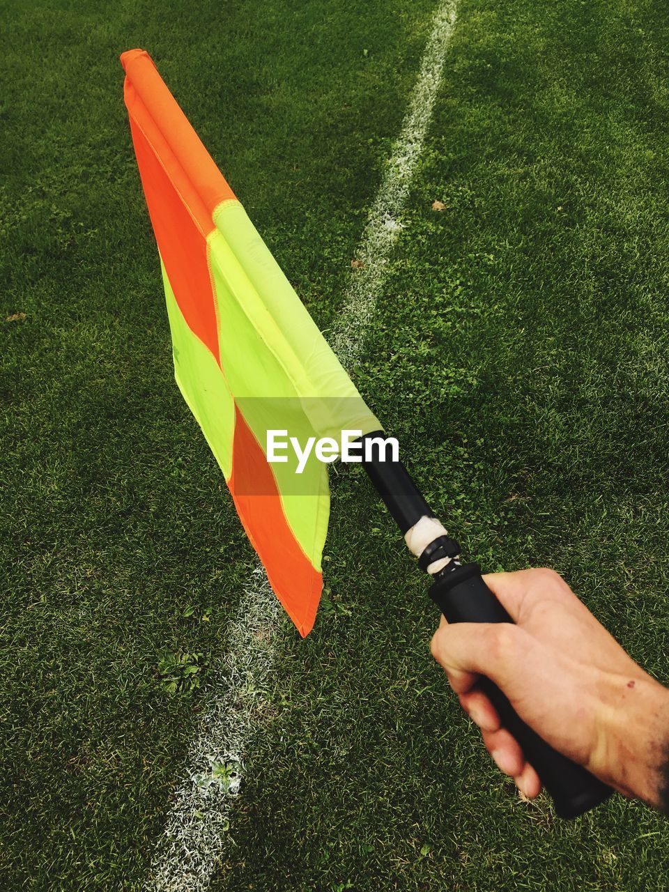 Cropped hand of line official holding flag on soccer field