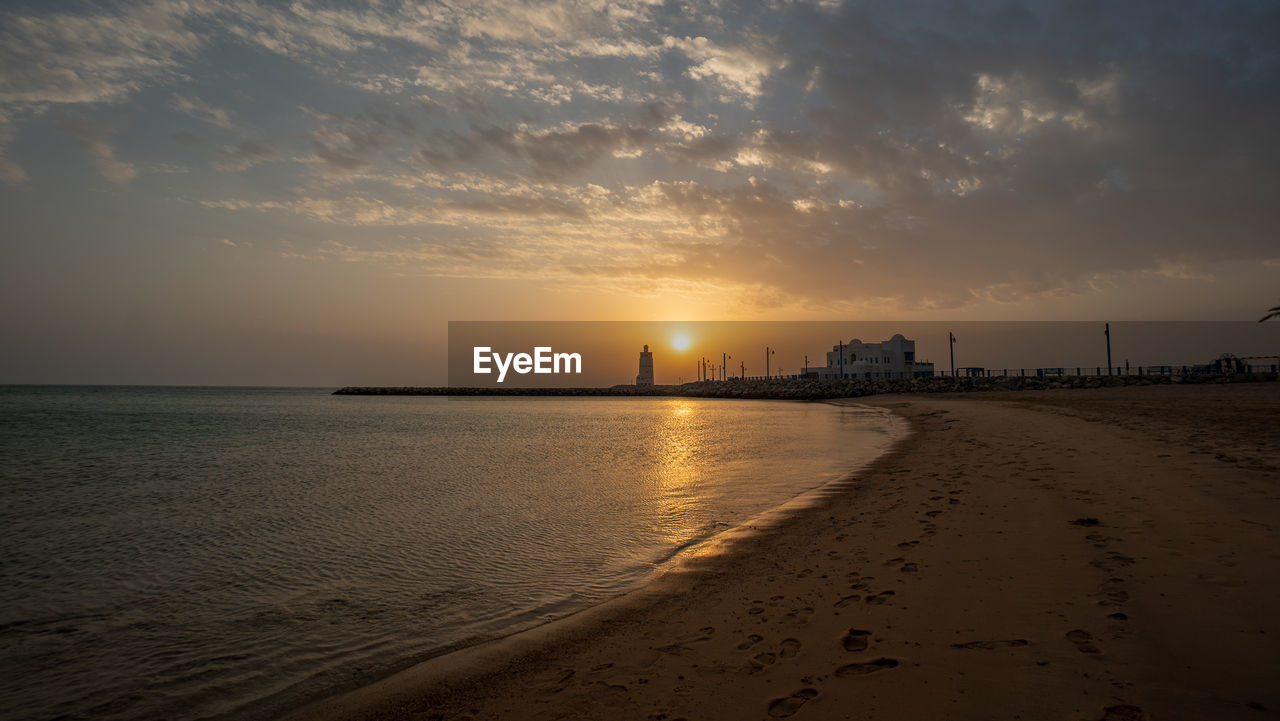 SCENIC VIEW OF BEACH AGAINST SKY AT SUNSET