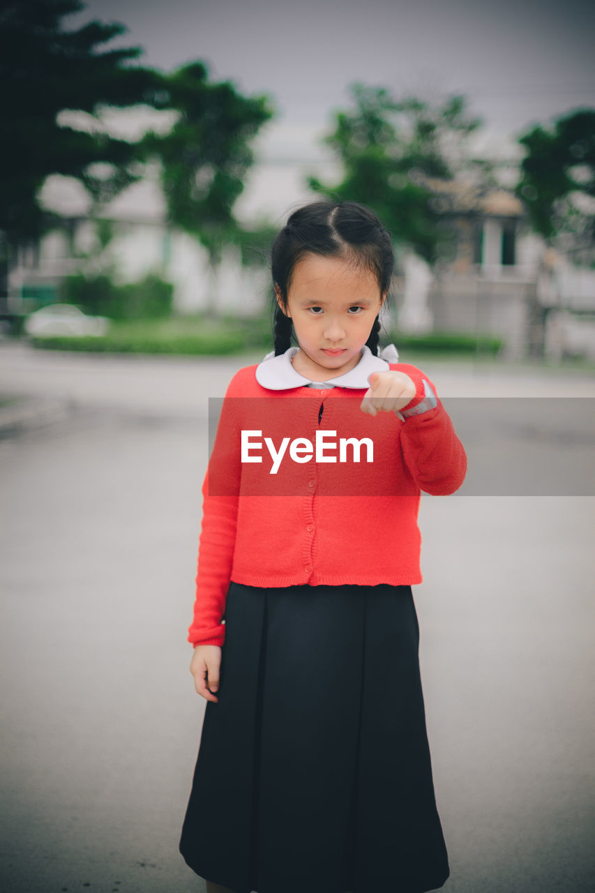 Portrait of cute girl pointing while standing on road