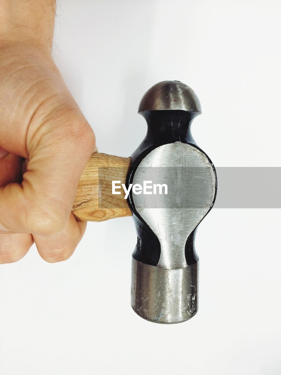 Cropped image of hand holding hammer against white background