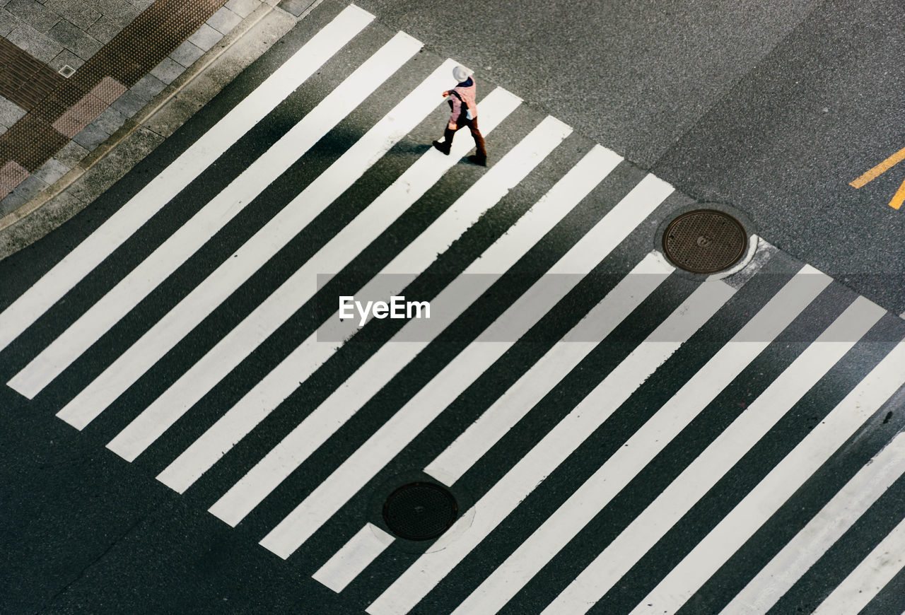 High angle view of woman walking on zebra crossing
