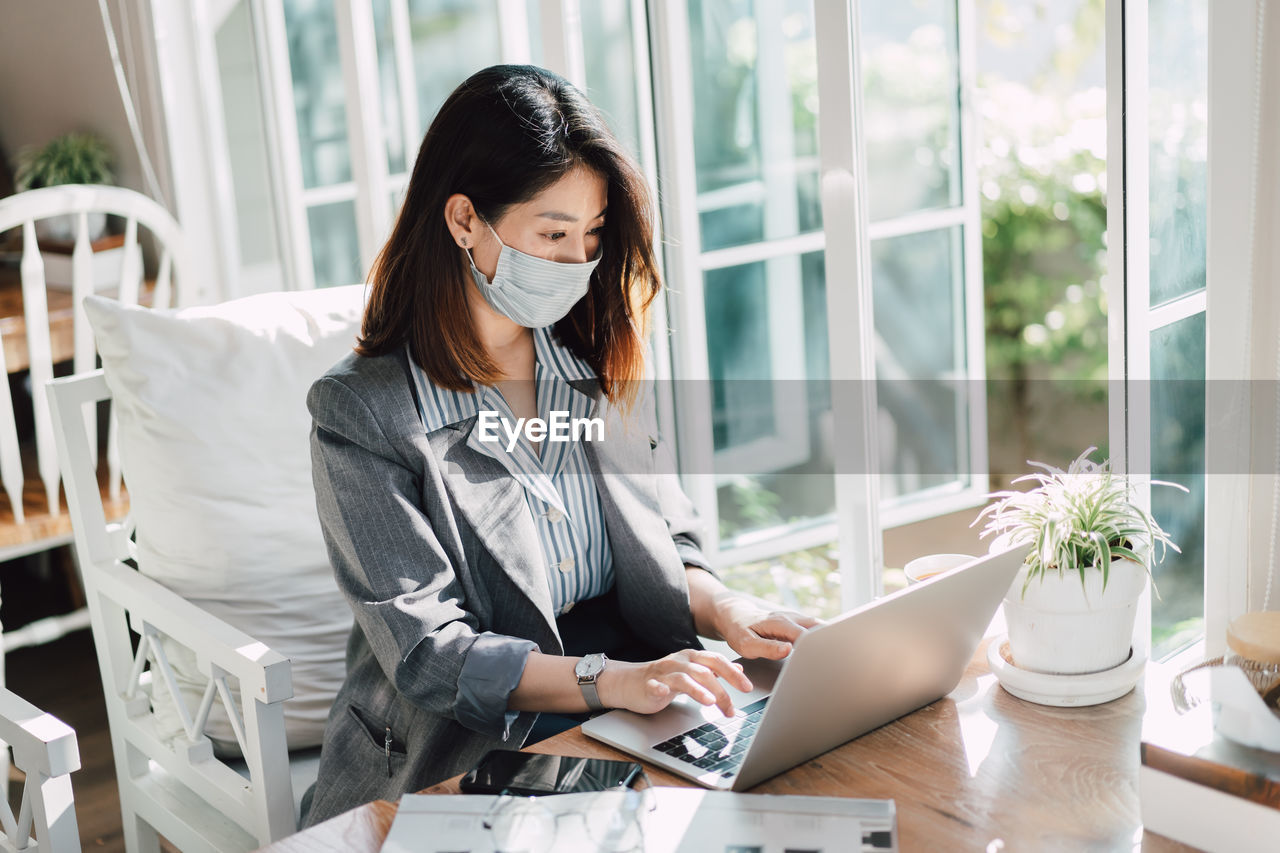 Young woman using mobile phone at table