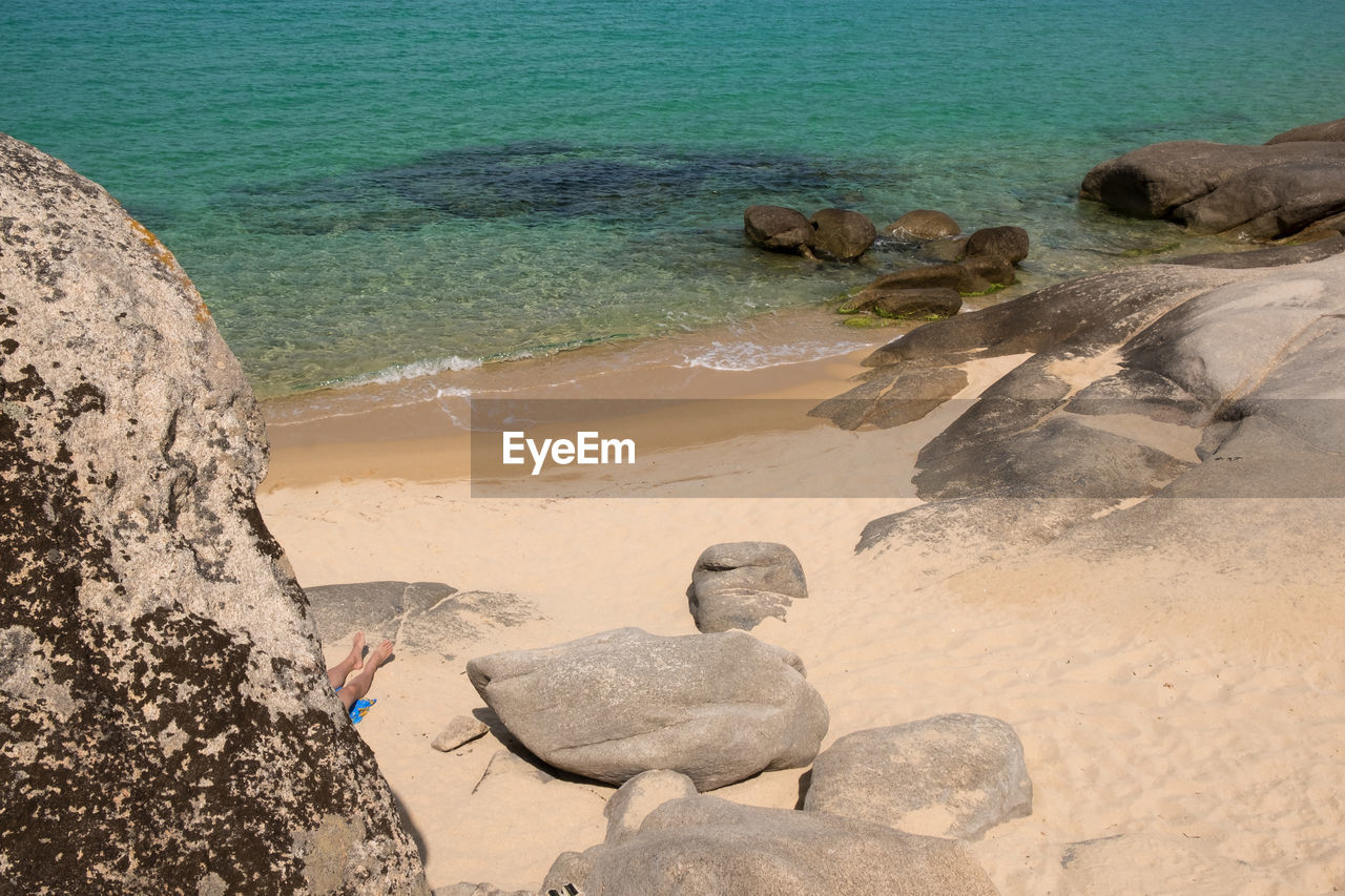 High angle view of person relaxing by rock at beach