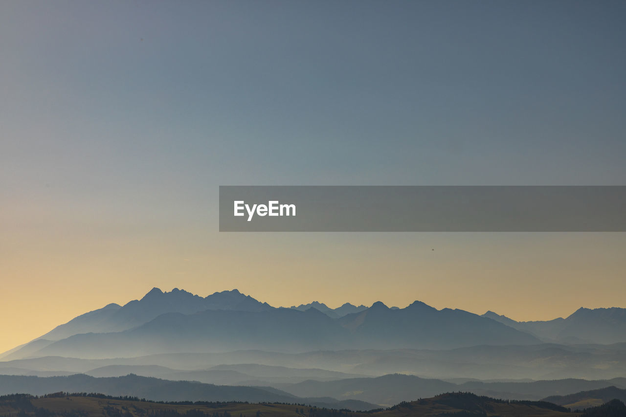 Scenic view of silhouette mountains against clear sky during sunset