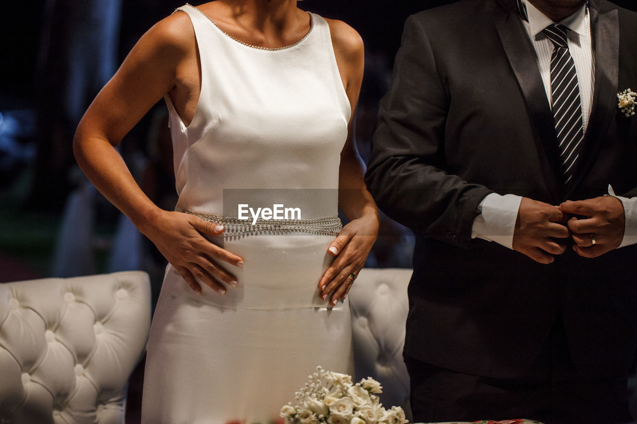 Midsection of bride and groom at wedding ceremony