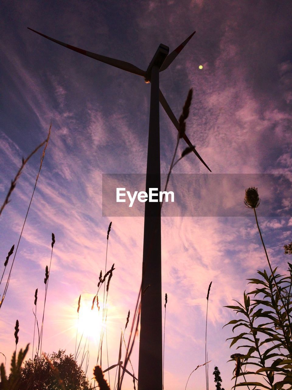 Low angle view of silhouette windmill against cloudy sky during sunset