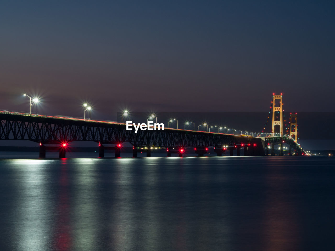 Illuminated mackinac bridge over strait at night