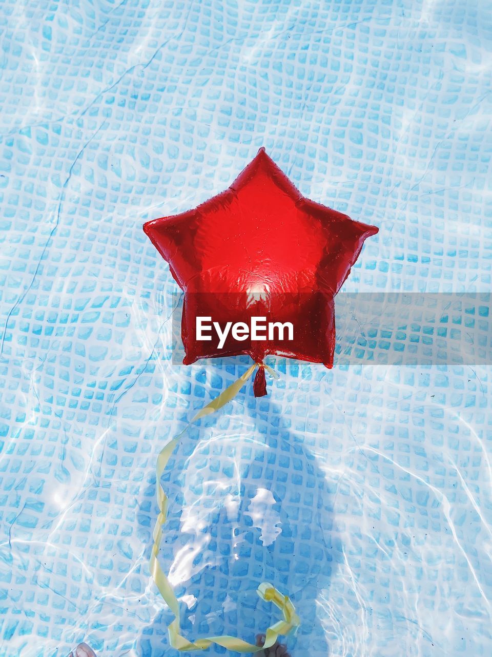 High angle view of red star shape balloon floating on swimming pool