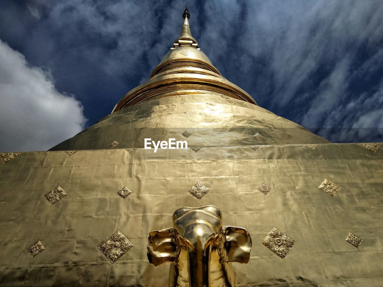 Low angle view of buddha statue against sky