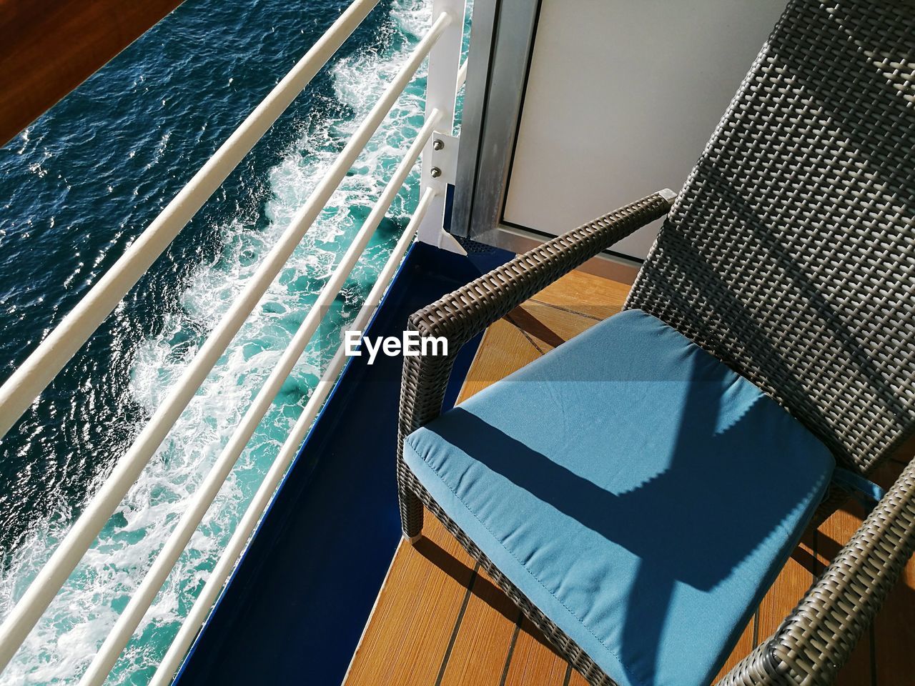 High angle view of empty chair on ship balcony by sea