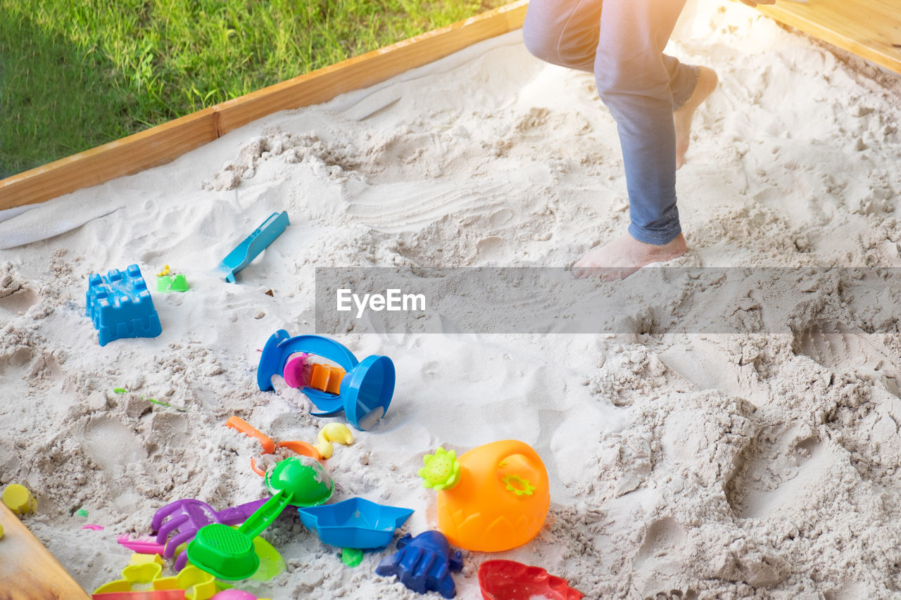 Low section of person playing with toys on sand at playground