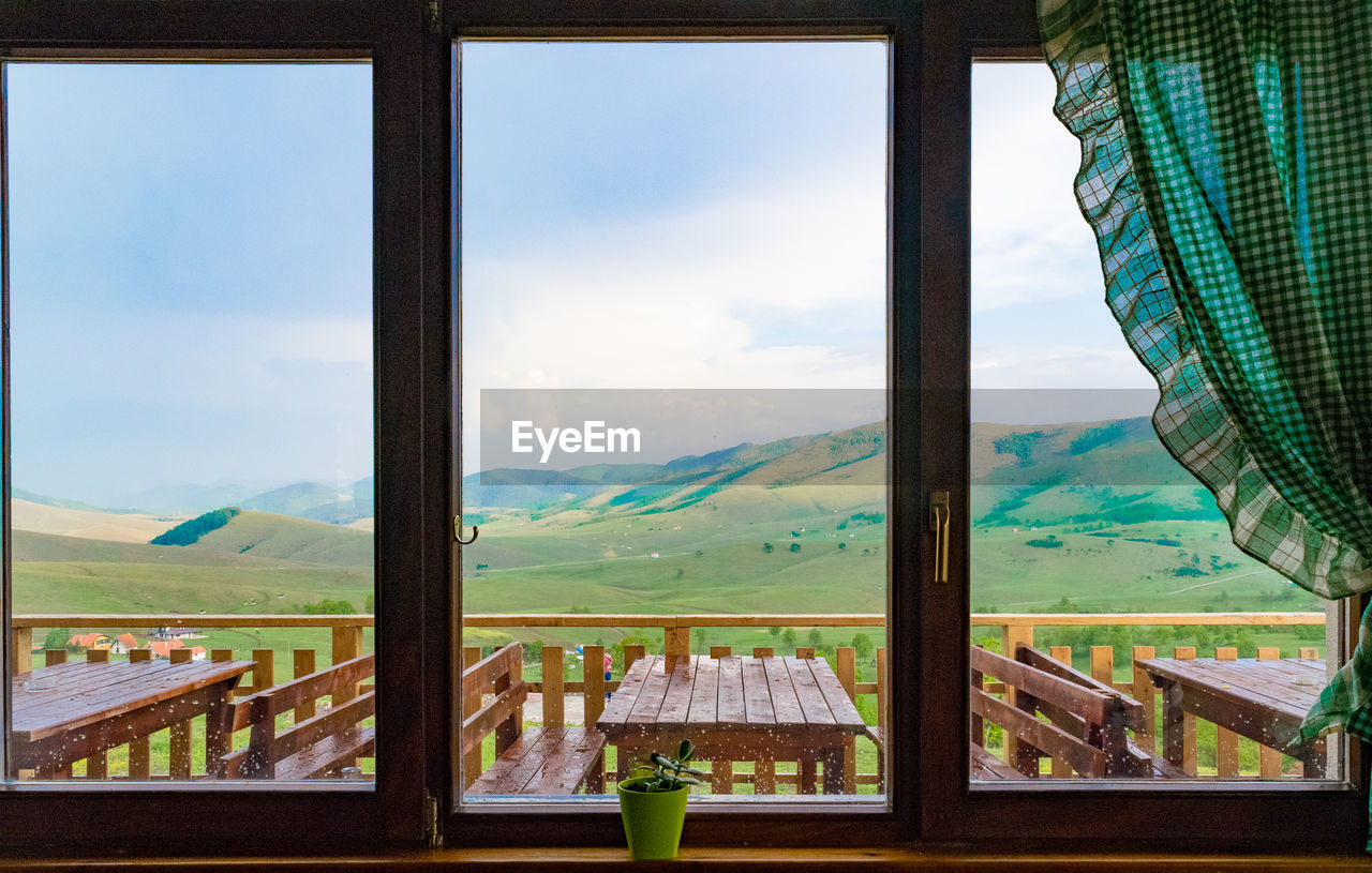 Scenic view of mountains against sky seen through window