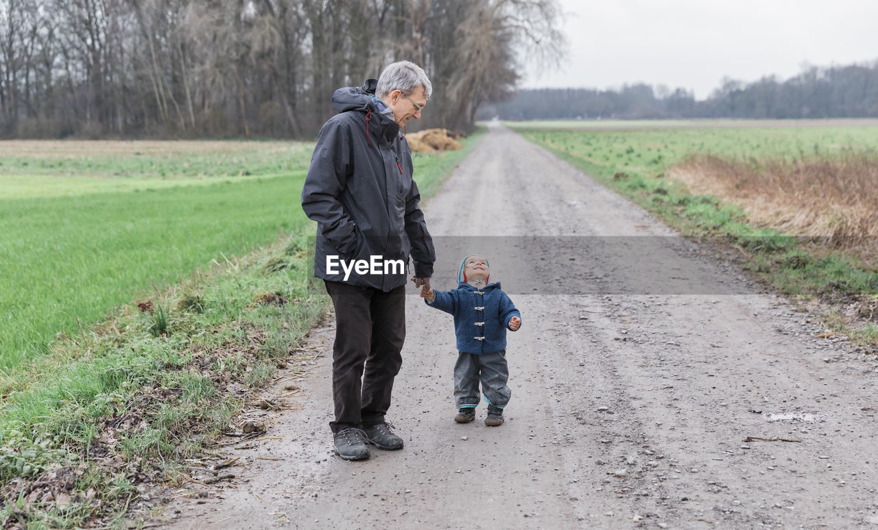 Full length of father and daughter on road amidst field