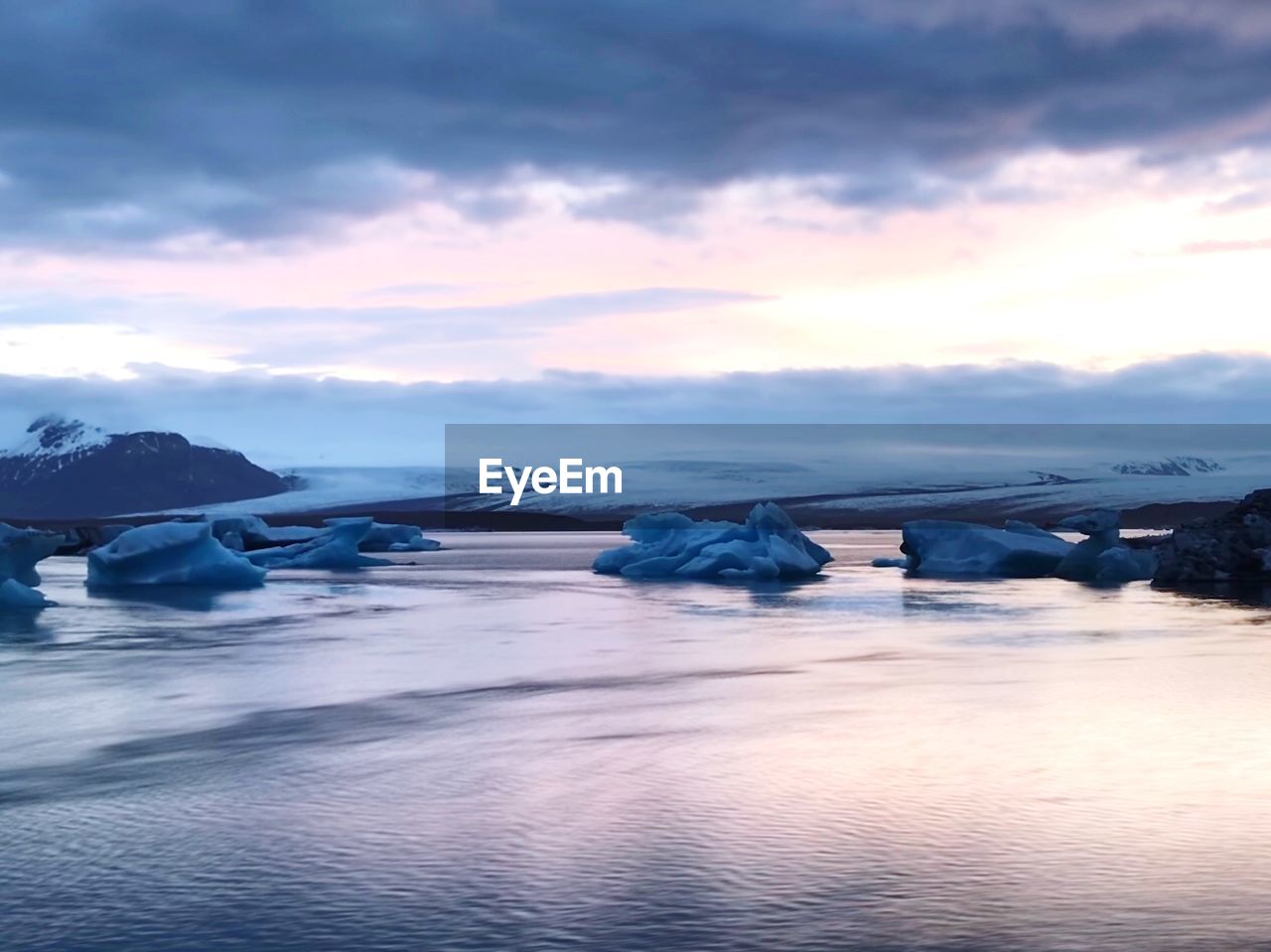 Icebergs in sea against sky during sunset