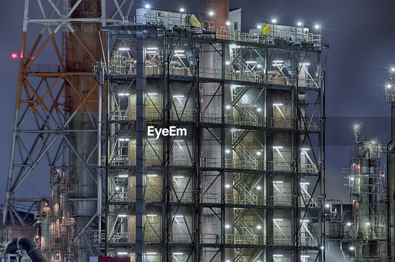 Low angle view of illuminated chemical plants against sky at night