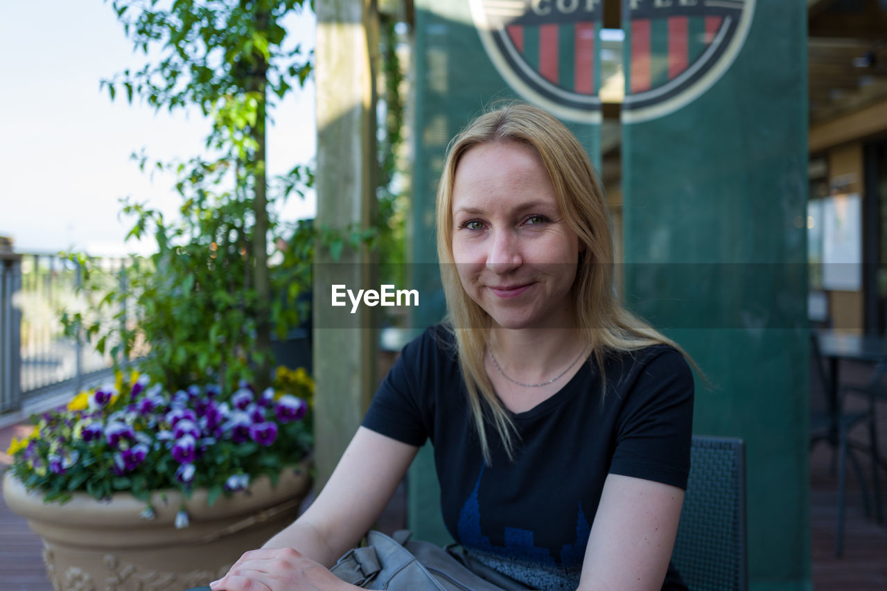 Portrait of smiling woman sitting at sidewalk cafe