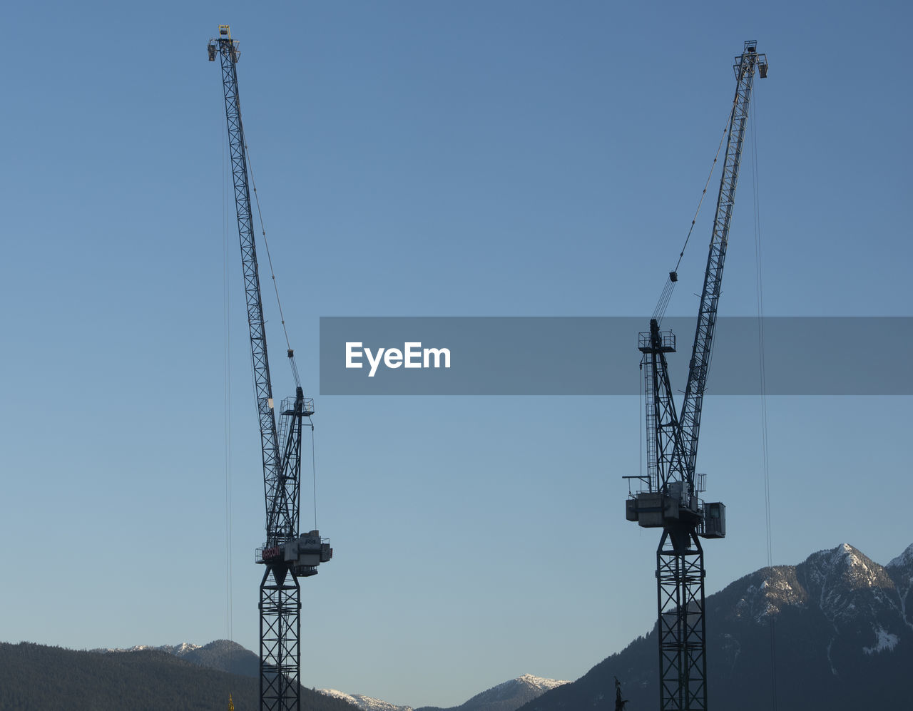 LOW ANGLE VIEW OF CRANES AGAINST CLEAR SKY