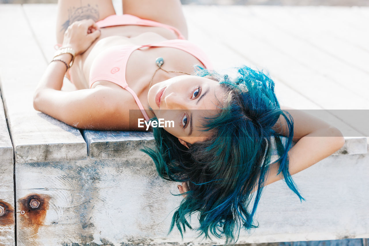 Portrait of woman in bikini lying on pier