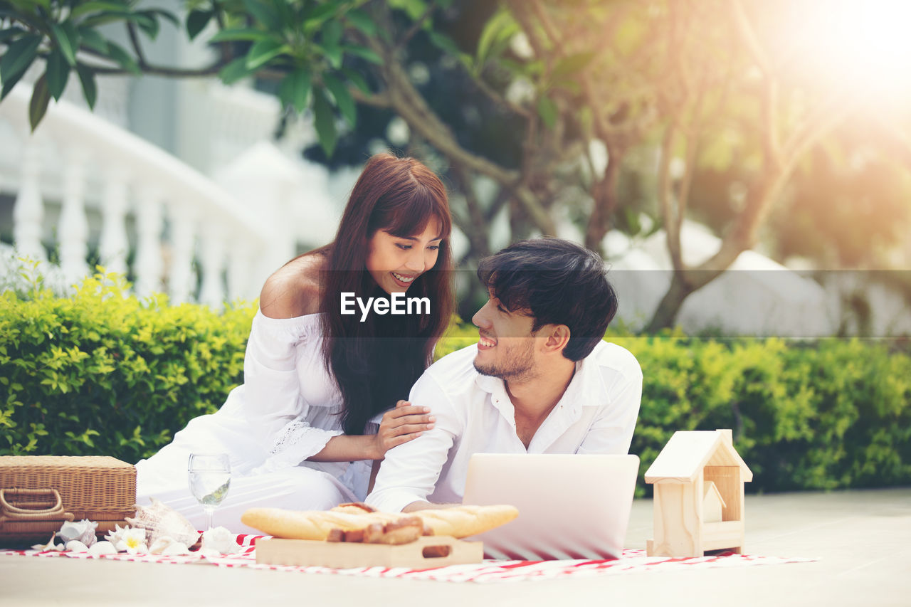 Smiling young couple looking at each other while spending leisure time outdoors