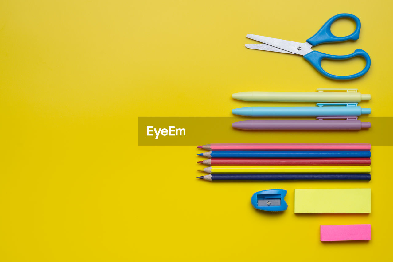 Directly above shot of school supplies on yellow background