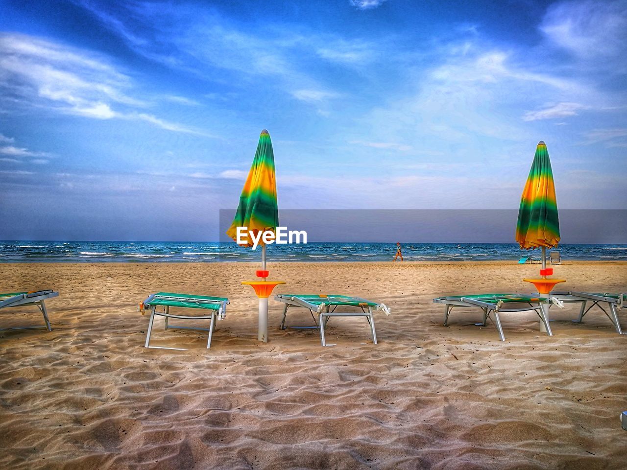 DECK CHAIRS ON BEACH BY SEA AGAINST SKY