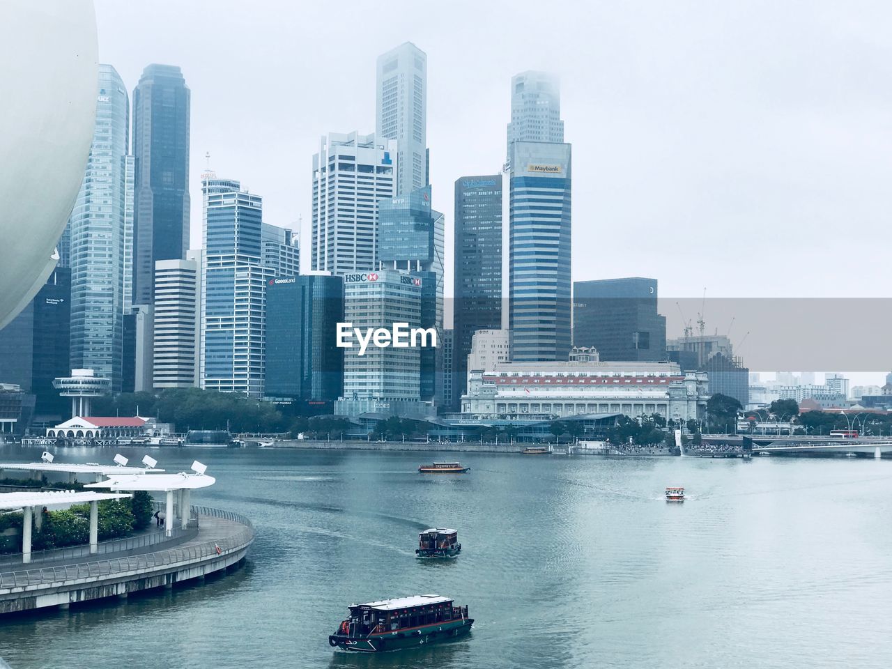 Boats in river by buildings in city against sky