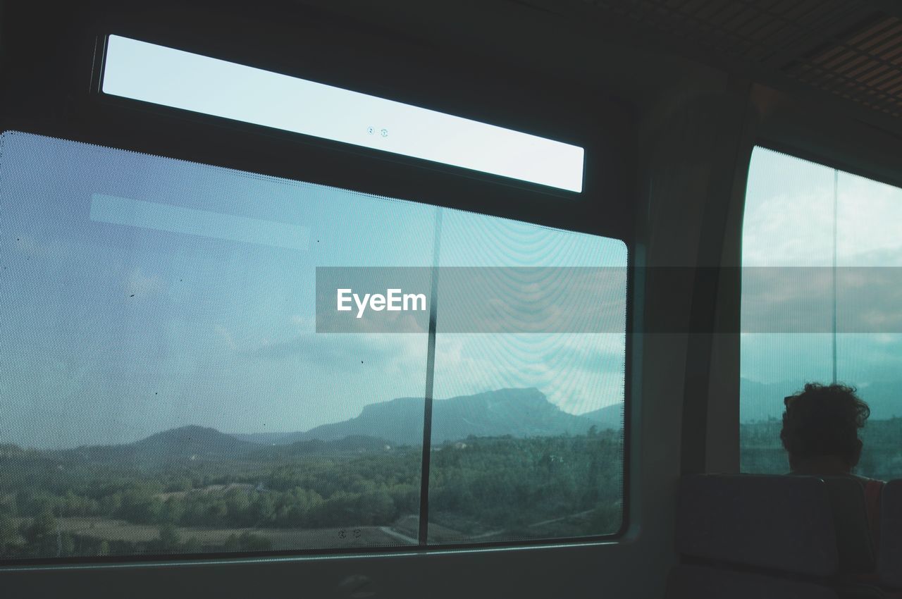 Landscape against cloudy sky seen from train window