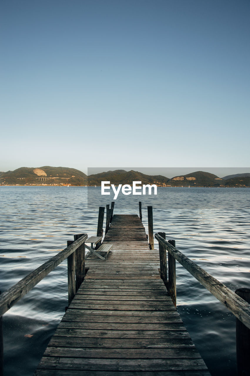 Pier over lake against clear sky