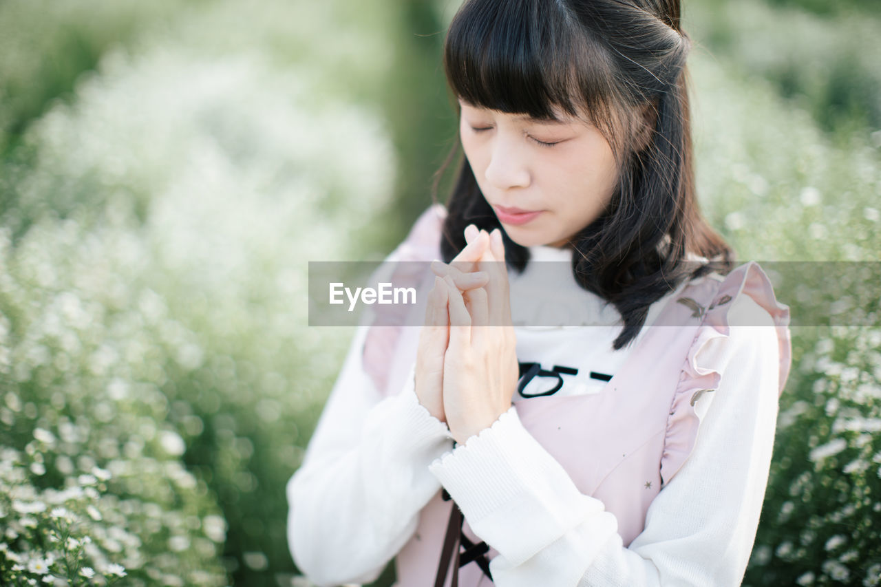 Woman praying while standing amidst plants