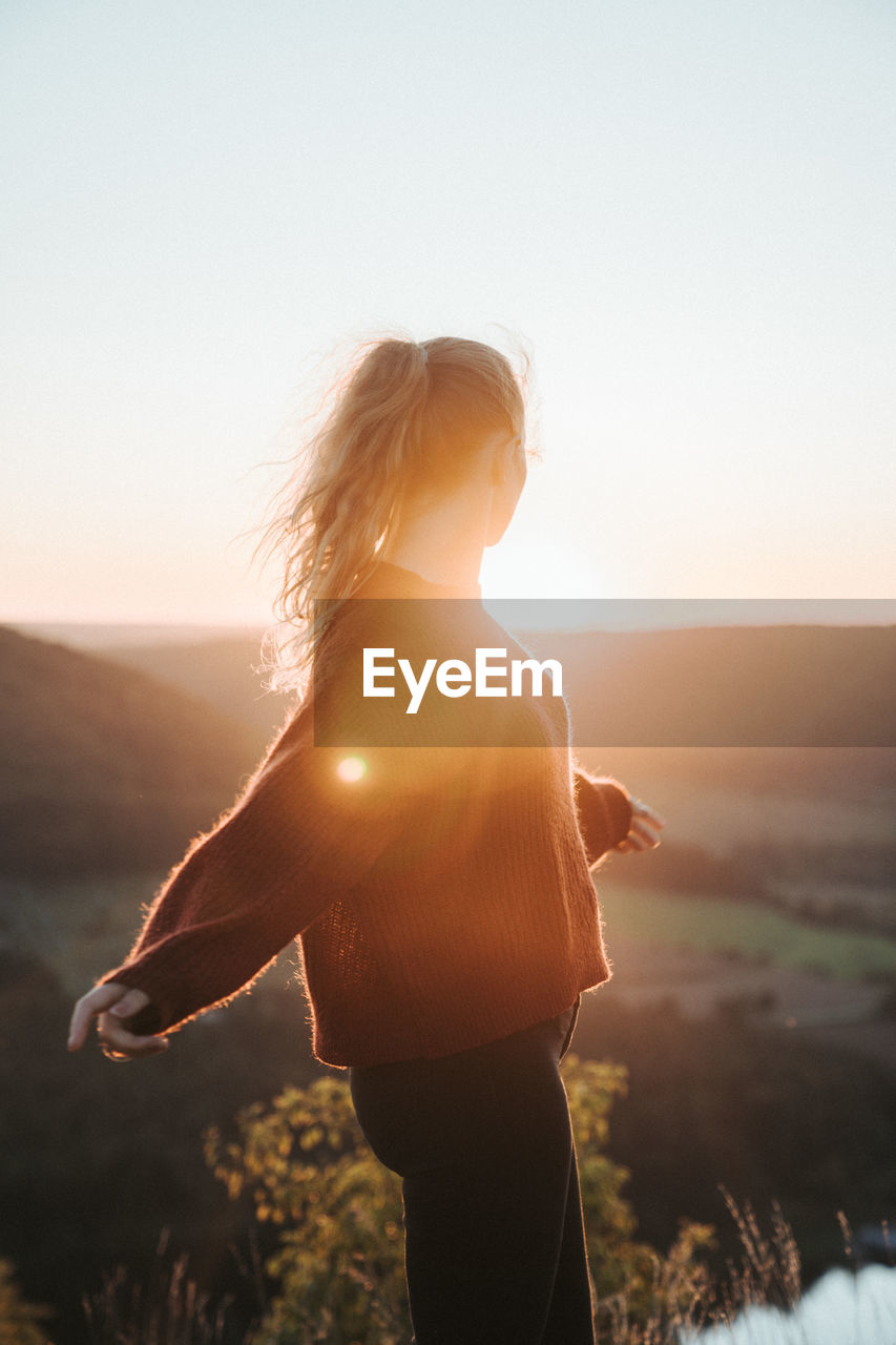 WOMAN LOOKING AT CAMERA AGAINST SKY