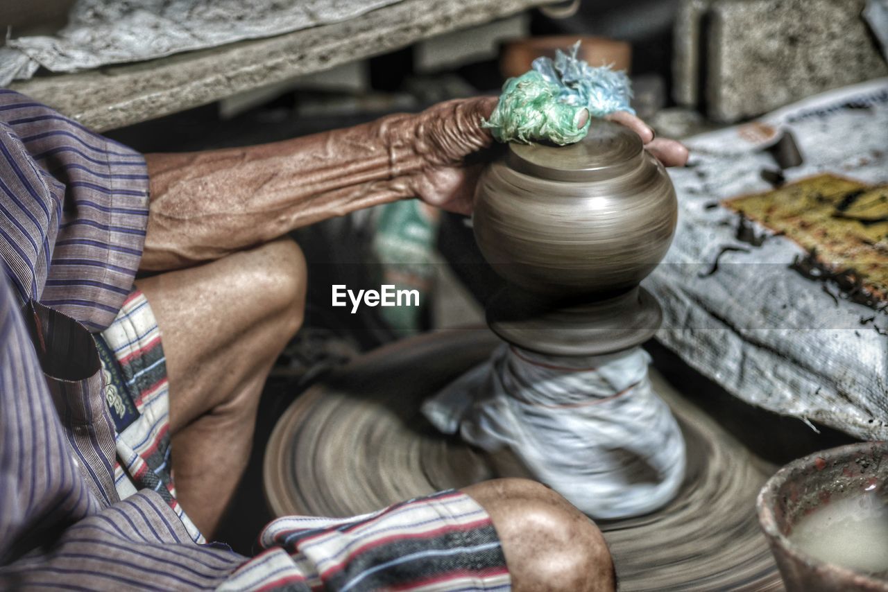 Midsection of man working on pottery wheel