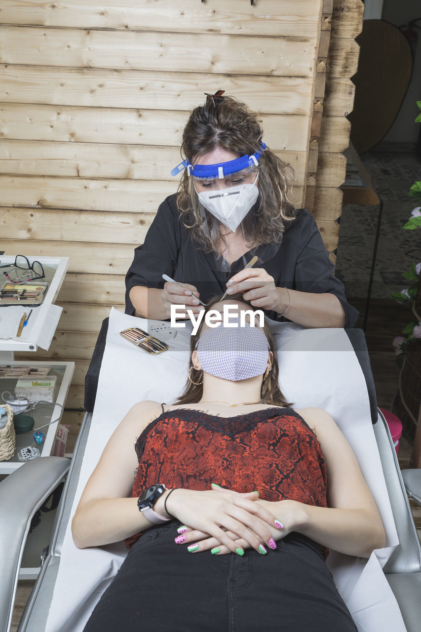 Beautician working with mask and protective screen for the virus covid