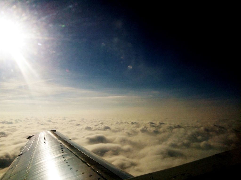 Cropped image of airplane wing cloudy sky