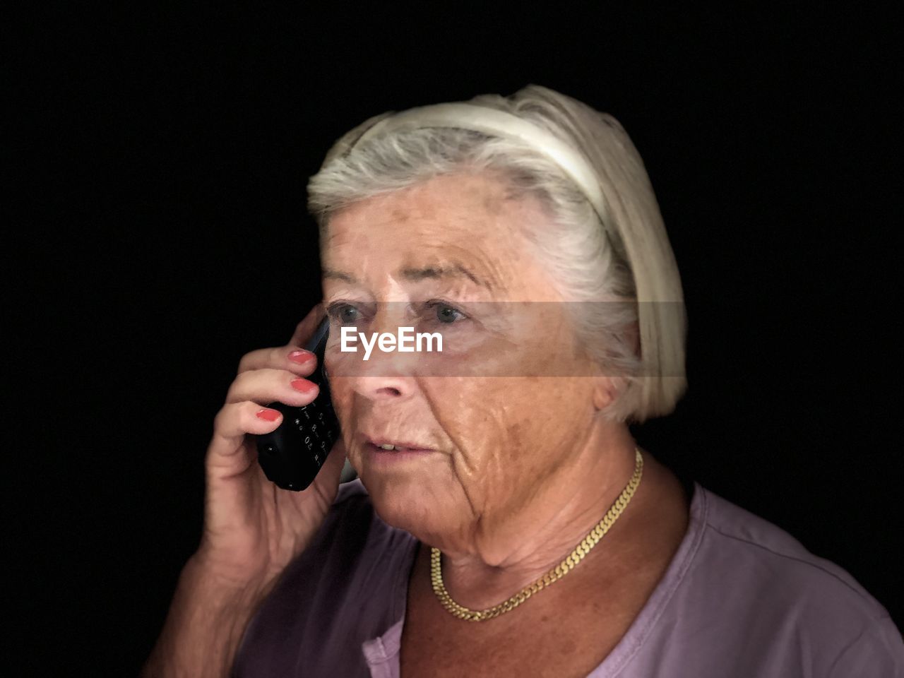 Woman talking on phone against black background