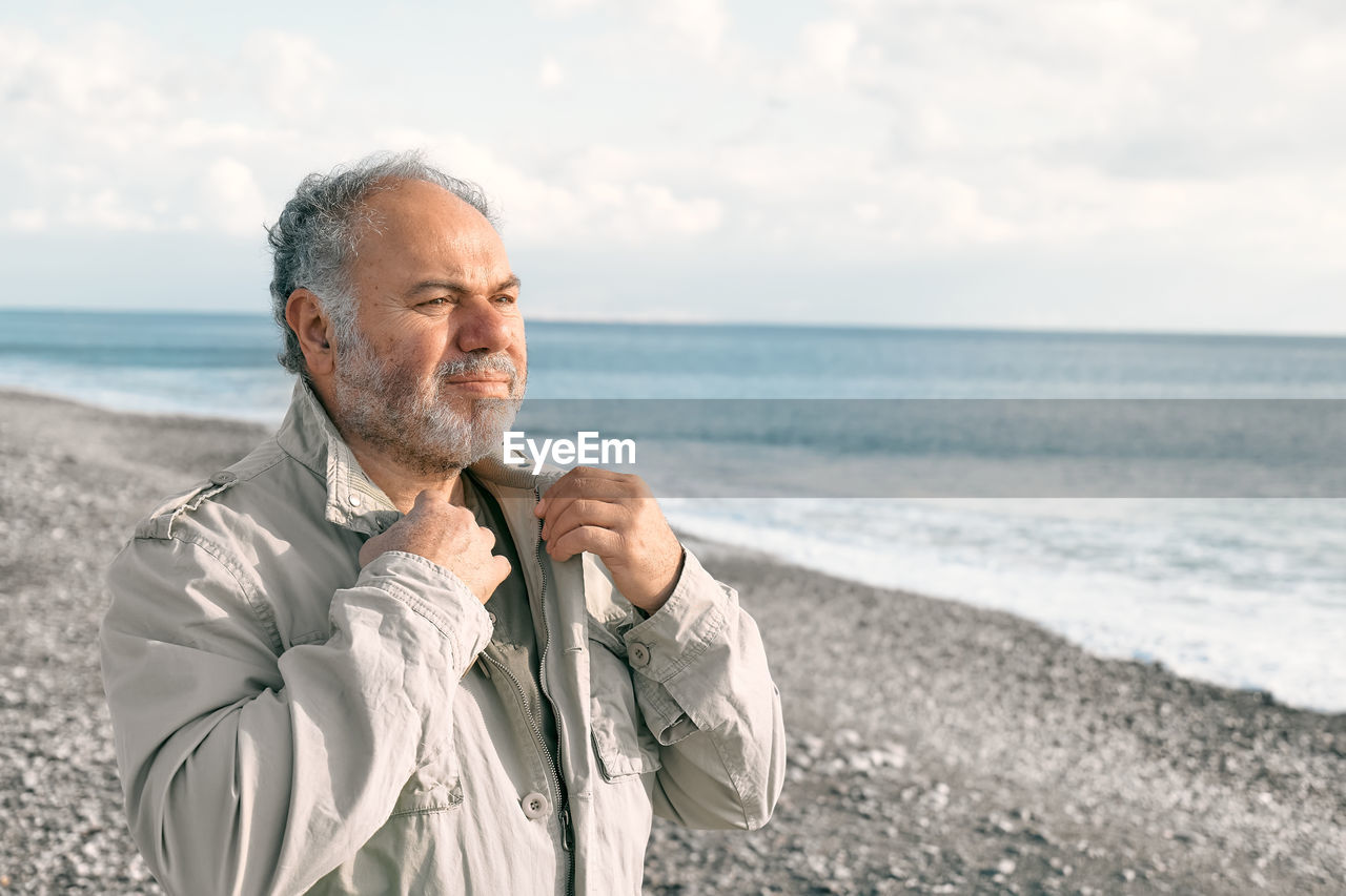 Happy middle-aged bearded man walking along deserted winter beach. concept of leisure activities