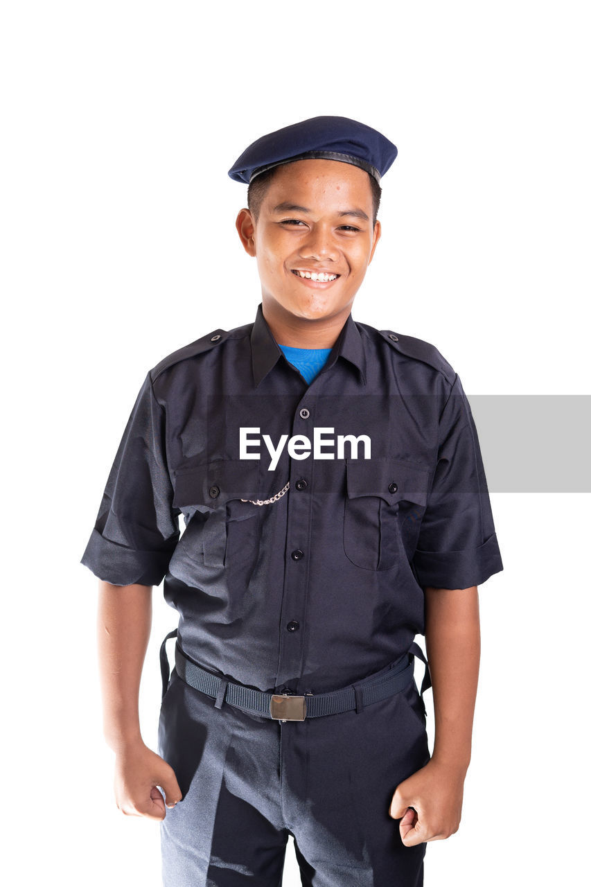 Portrait of boy in uniform standing against white background